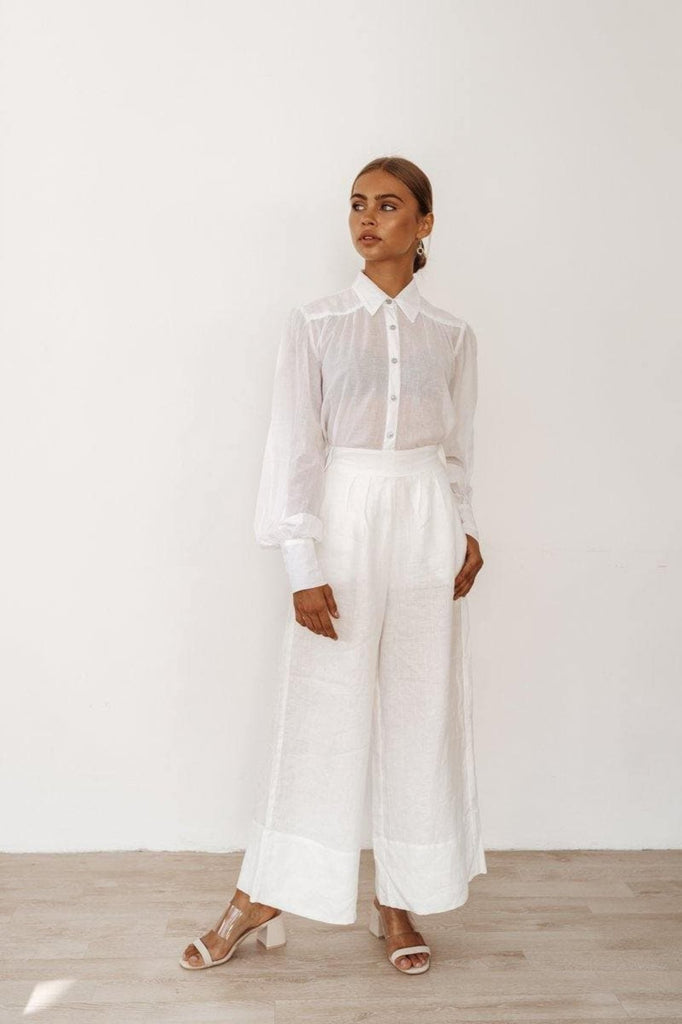 woman in a linen shirt is wearing also white trousers resembling traditional bohemian style